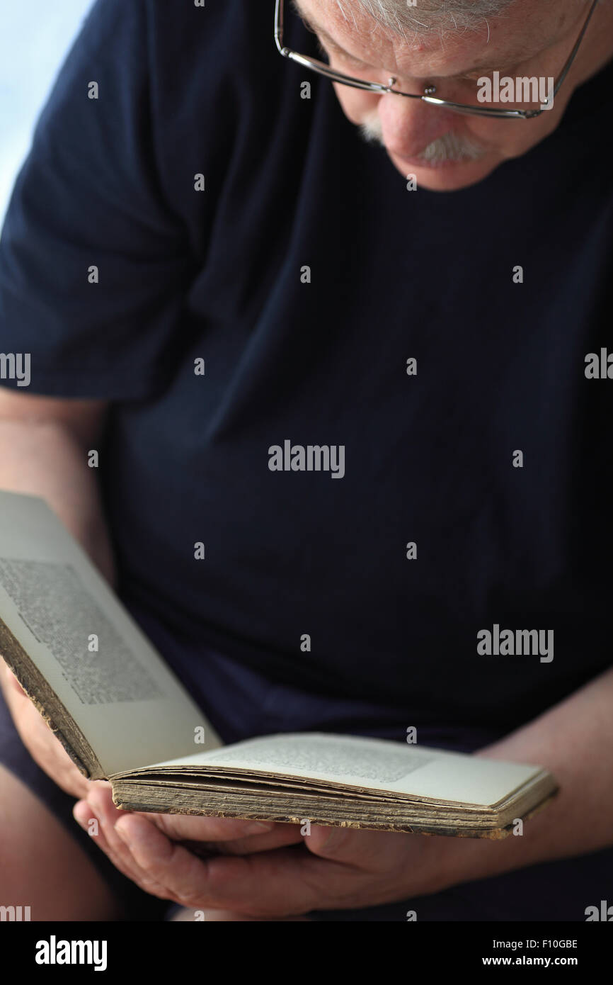 Älterer Mann ein Buch lesen, aus einem dunklen Bereich für text Stockfoto