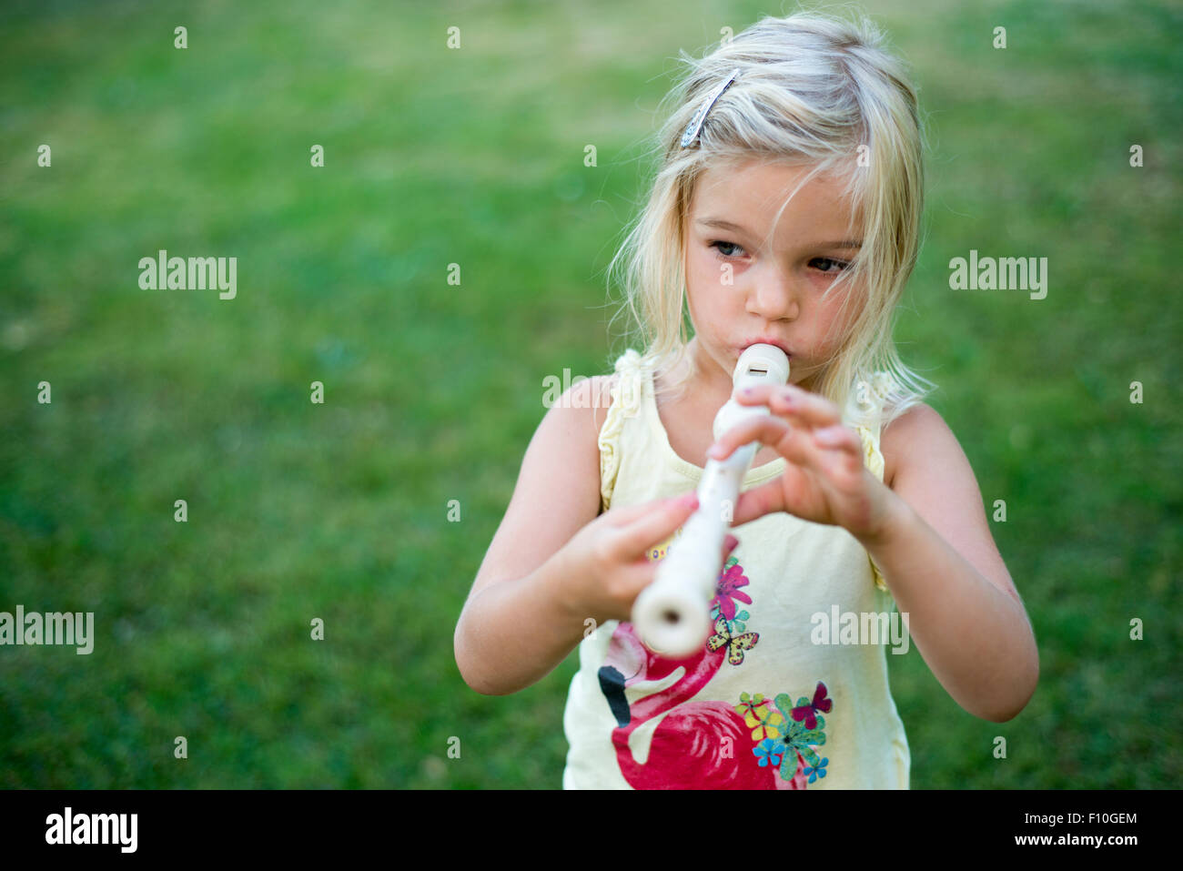 Kind blondes Mädchen spielen Querflöte Blockflöte, outdoor Portrait im Hinterhof Stockfoto