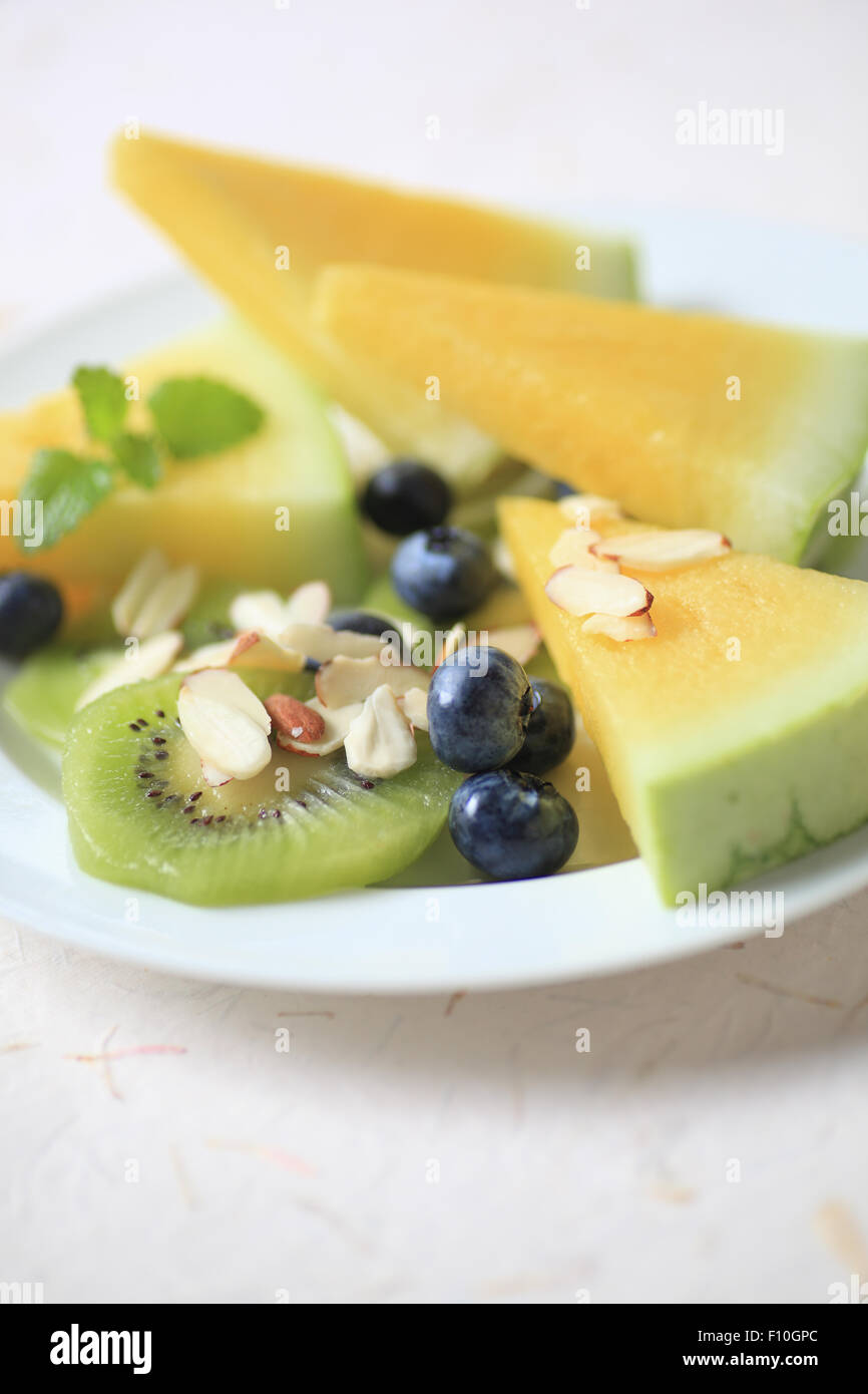 Frische gelbe Wassermelone mit Kiwi, Heidelbeeren und Mandelsplitter, Textfreiraum enthalten Stockfoto