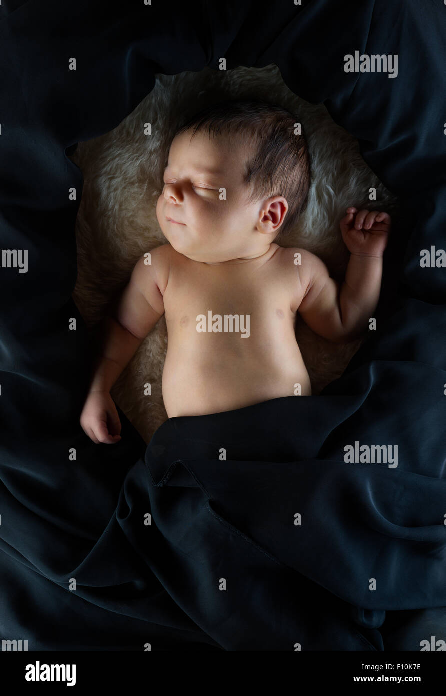 Niedliche neugeborenes Baby schlafen auf weiße Wolldecke, bedeckt mit schwarzem Stoff Stockfoto