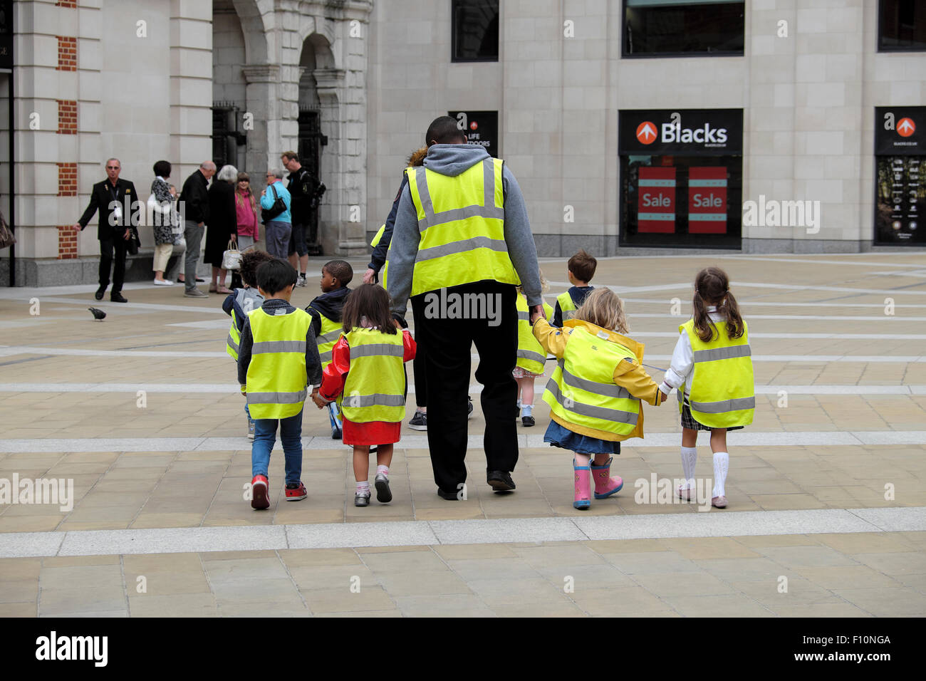 Kindergarten Kinder wandern mit tagesmütter tragen hohe Sichtbarkeit fluoreszierende Warnwesten auf einer Straße in der Londoner City UK KATHY DEWITT Stockfoto