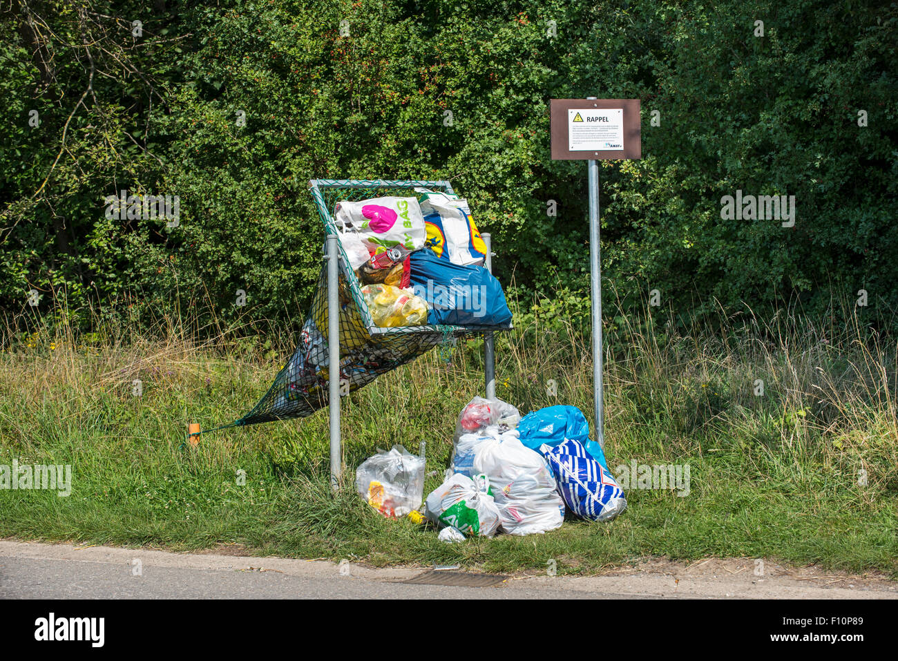 Illegale Ablagerung von Haushalt Müllsäcke in Net Straßenrand bedeutete für das werfen in Dosen und Plastikflaschen Stockfoto