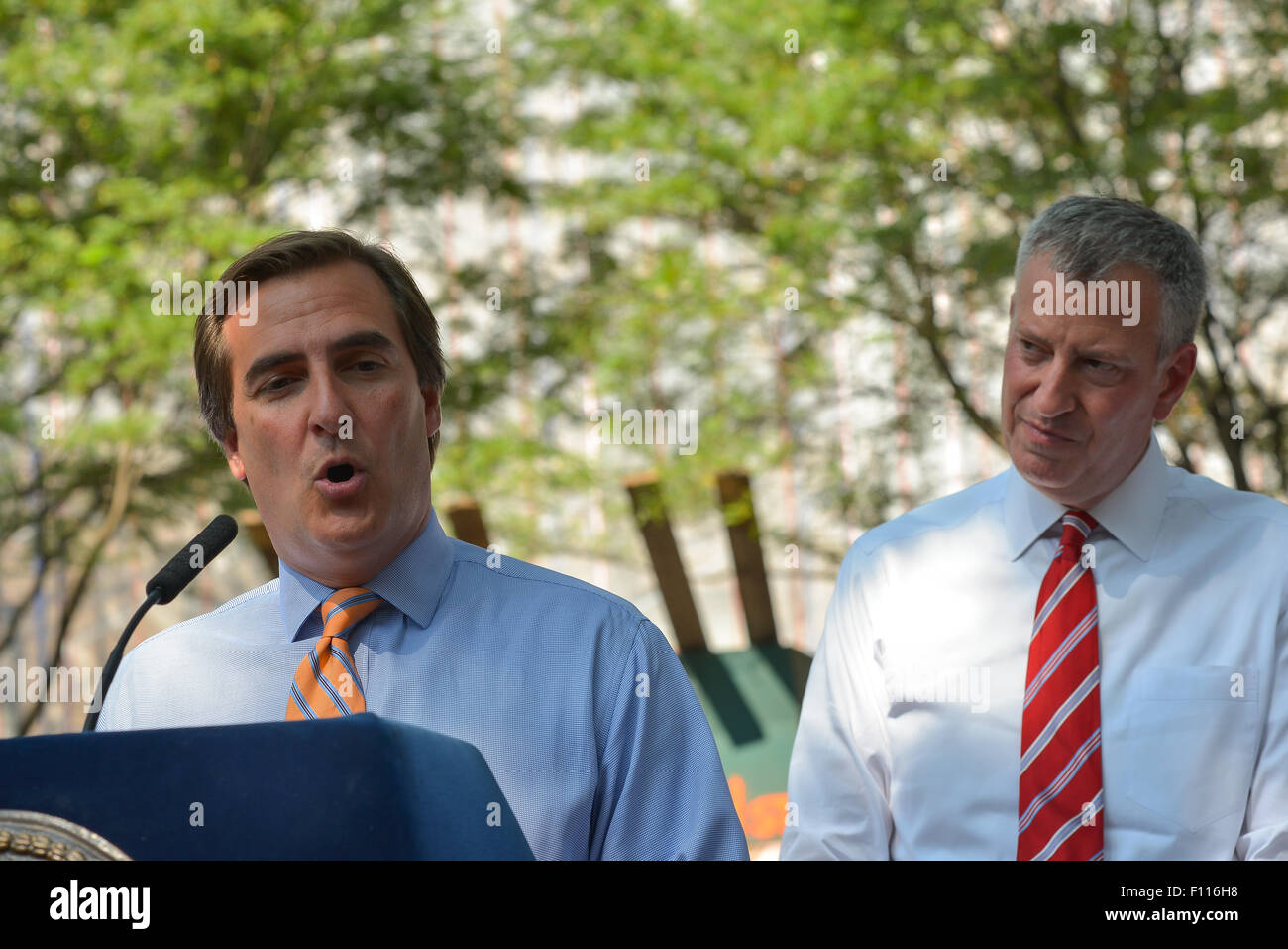 New York, Vereinigte Staaten von Amerika. 24. August 2015. NY State Senator Michael Gianaris (links) spricht bei der NYCHA Wartung Finanzierung Ankündigung als Bürgermeister de Blasio hört. Bürgermeister Bill de Blasio gemeinsam mit ausgewählten Bundes-, bundesstaatlichen und lokalen Beamten, die Ersetzung der Dächer in den NYCHA Queensbridge Häusern, die Nationen größte öffentliche Wohnanlage, bekannt zu geben und zu erklären, die Ziele der "NextGeneration NYCHA" Sozialwohnungen neu zu beleben. Bildnachweis: Albin Lohr-Jones/Pacific Press/Alamy Live-Nachrichten Stockfoto