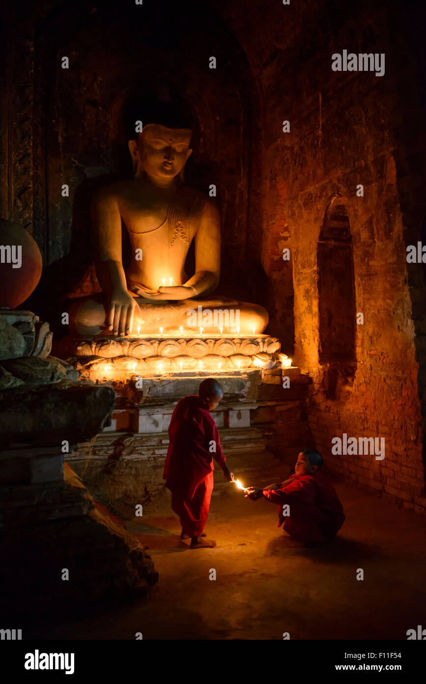 Asiatische Mönche in Ausbildung Anzünden von Kerzen an Buddha-Schrein Stockfoto