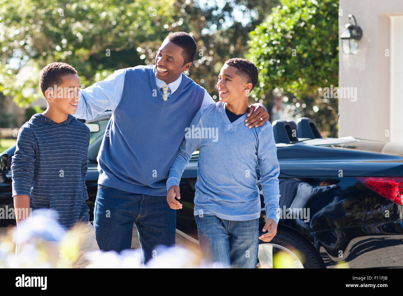 Vater umarmt Söhne in der Nähe von Auto Stockfoto