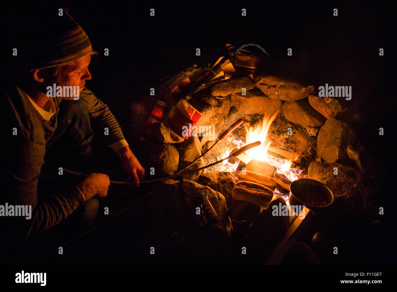 Kaukasischen Mann Essen über Lagerfeuer rösten Stockfoto