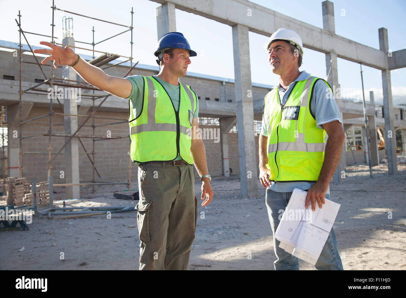 Kaukasische Bauarbeiter sprechen auf Baustelle Stockfoto