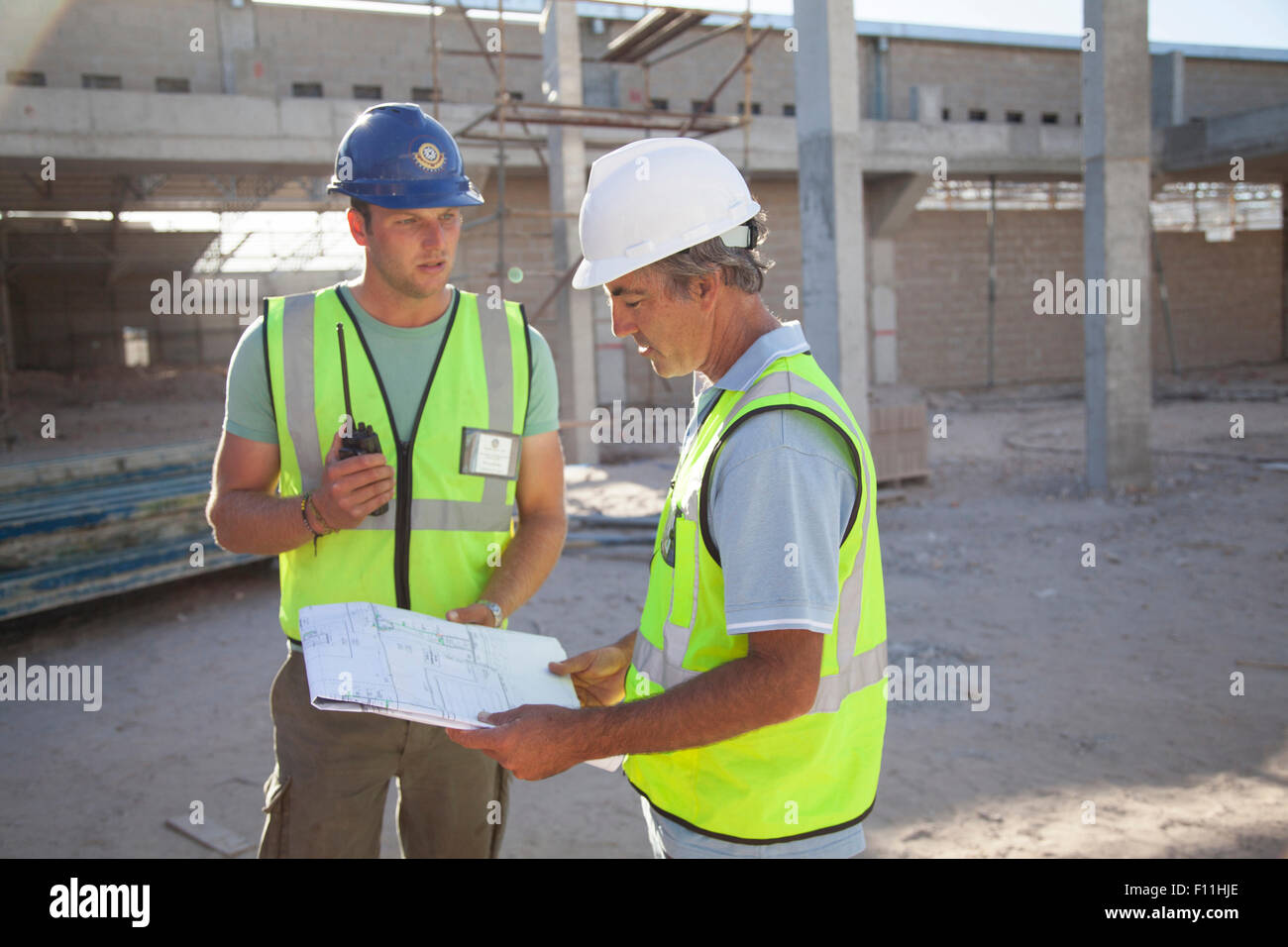 Kaukasische Bauarbeiter sprechen auf Baustelle Stockfoto