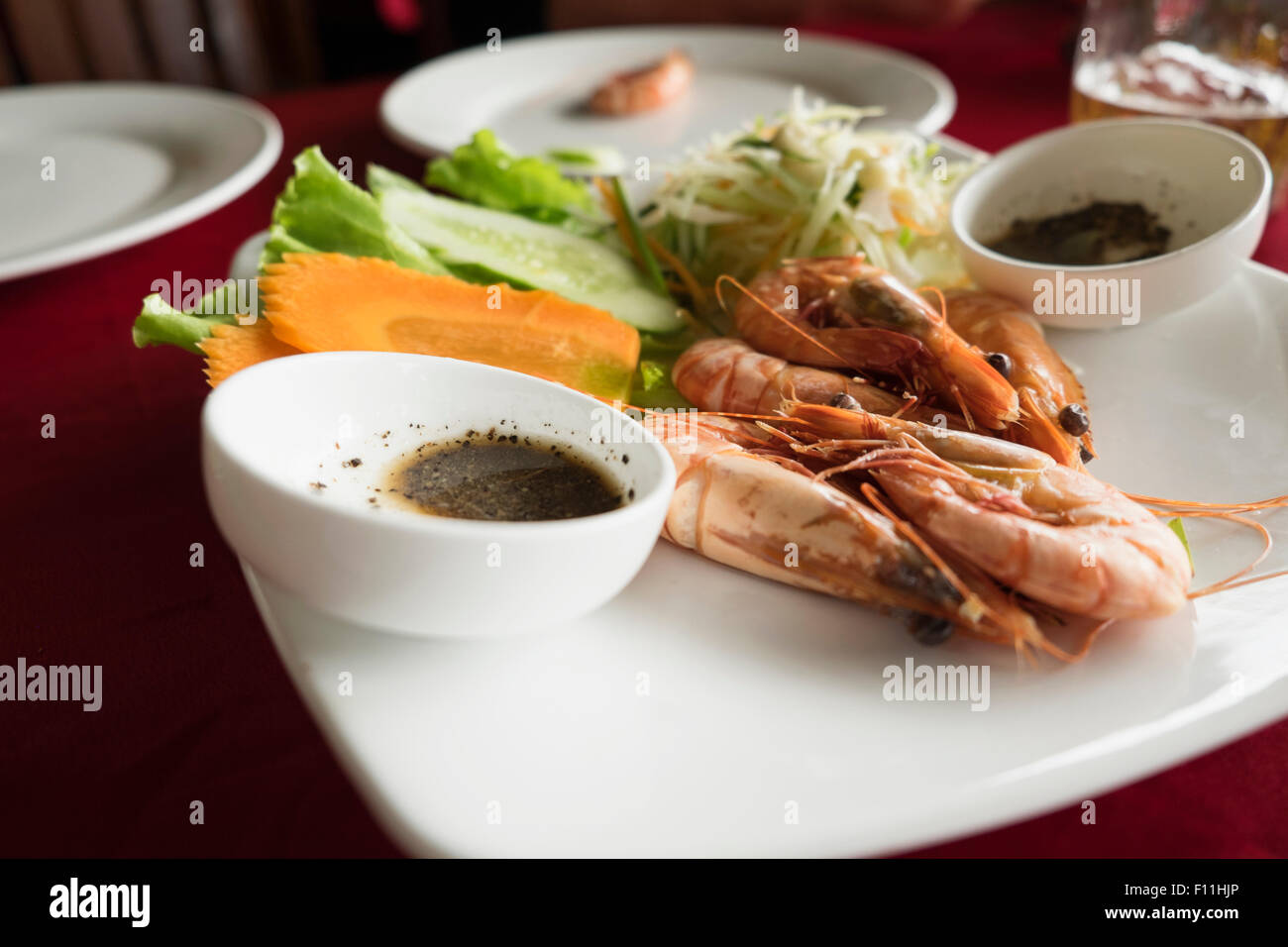 Teller mit Garnelen, Karotten und Salat am Tisch im restaurant Stockfoto