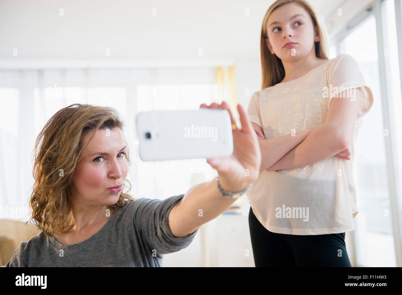 Kaukasische Mädchen peinlich Mutter unter Selfies mit Handy Stockfoto