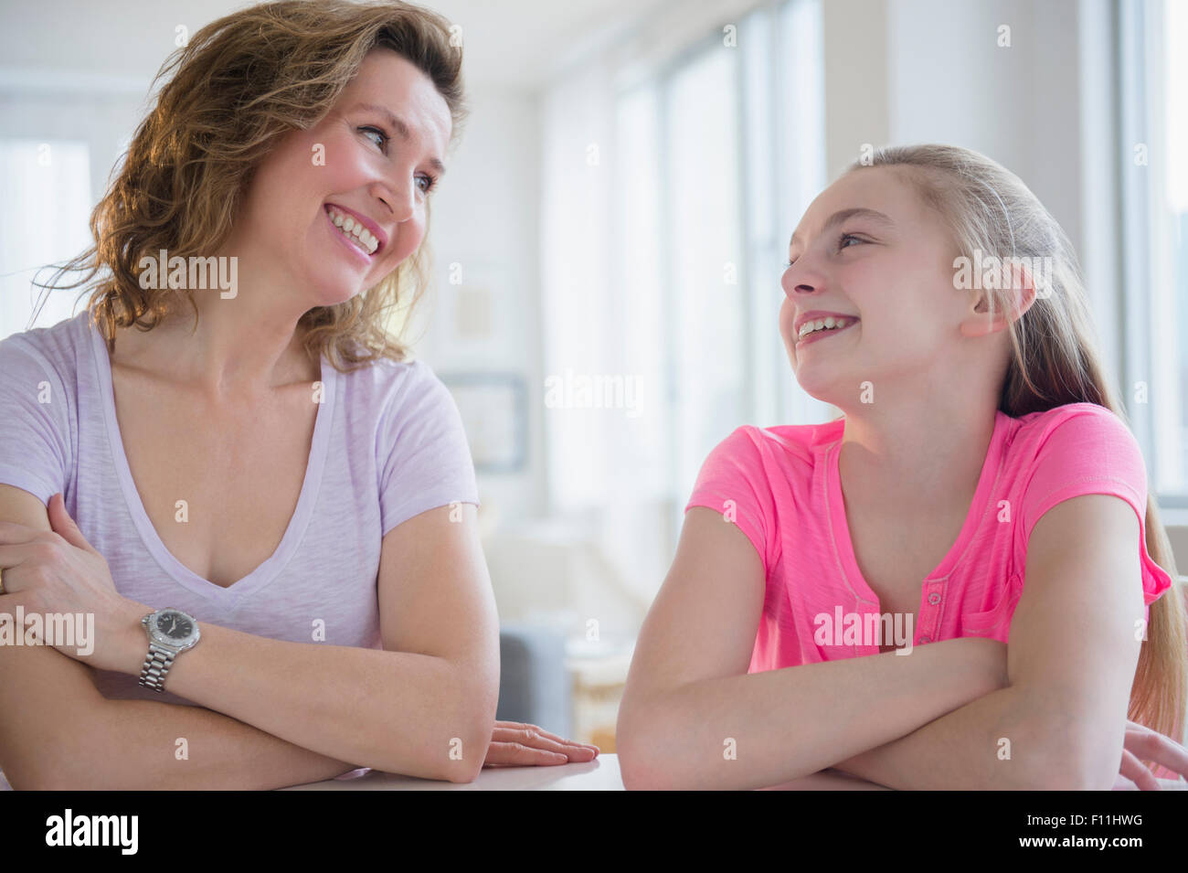 Kaukasische Mutter und Tochter lachend am Tisch Stockfoto