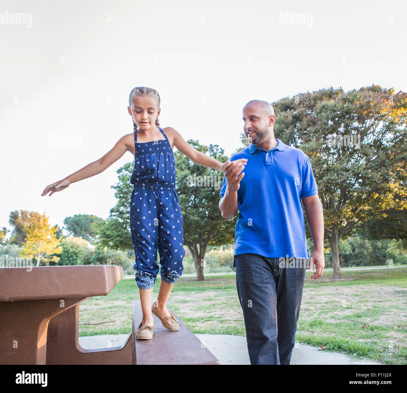Vater und Tochter auf Picknick-Tisch im Park spielen Stockfoto