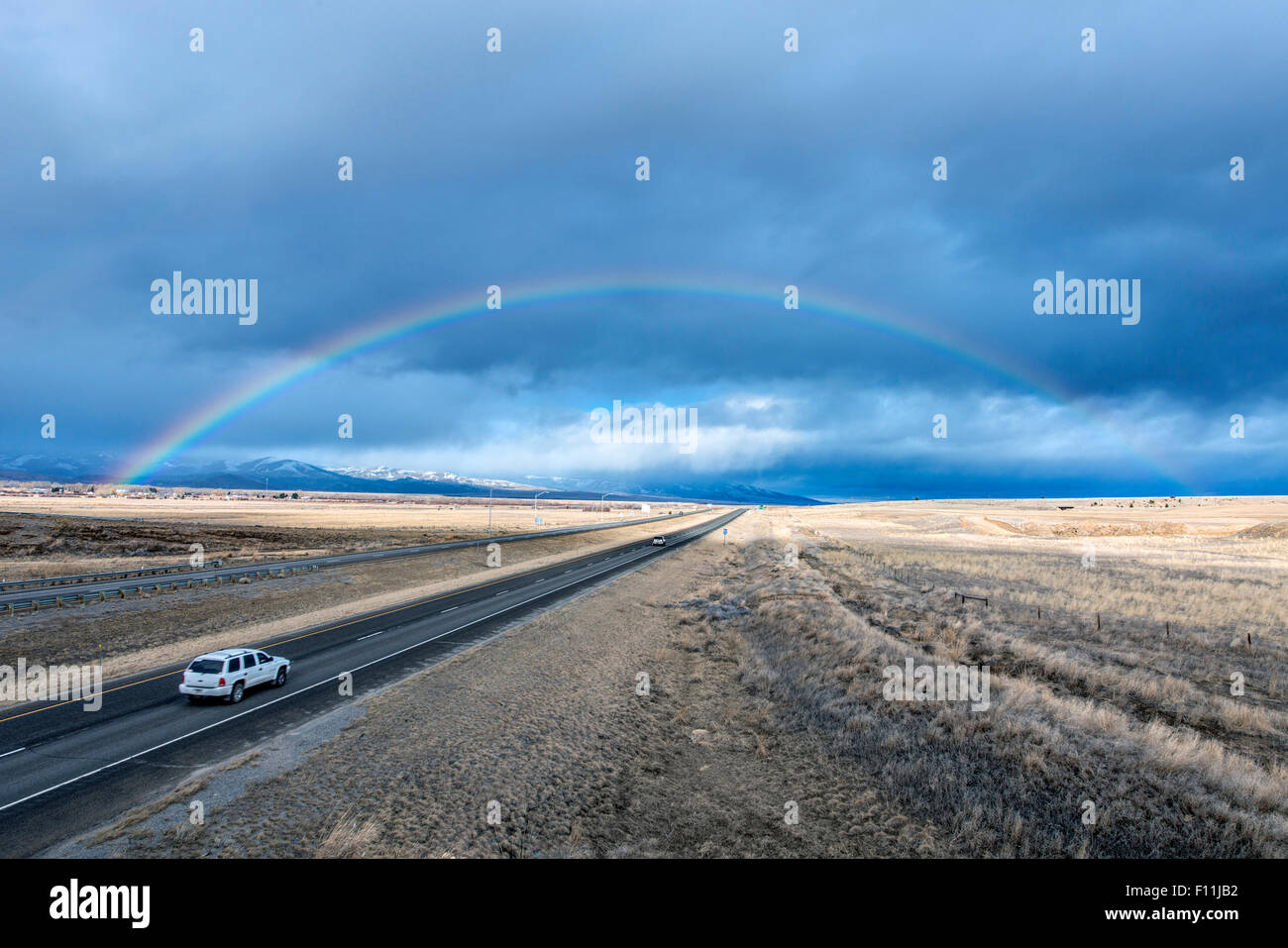 Vogelperspektive Blick auf Autofahren Rainbow auf remote-Straße Stockfoto