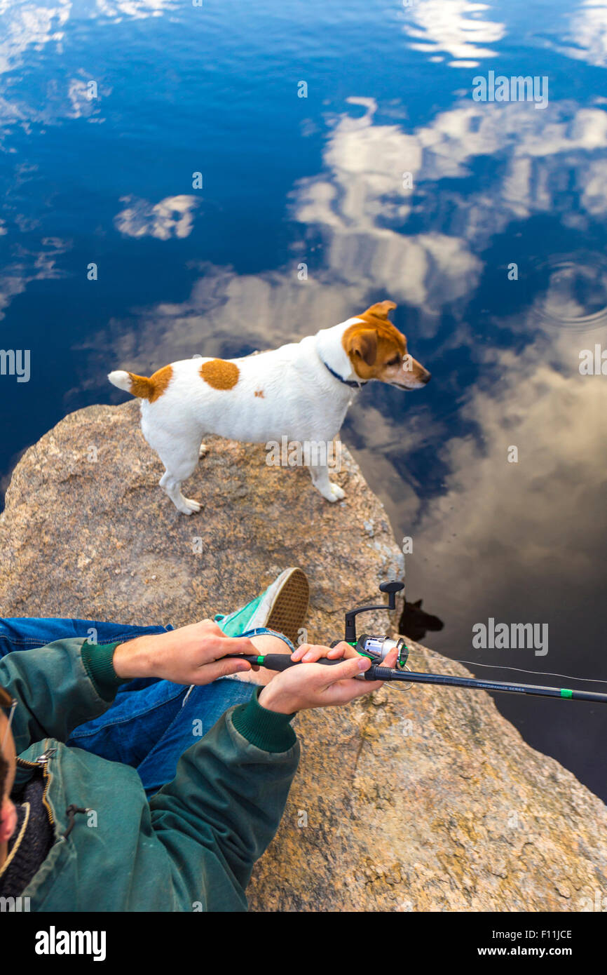 Kaukasischen Mann mit Hund in abgelegenen See angeln Stockfoto
