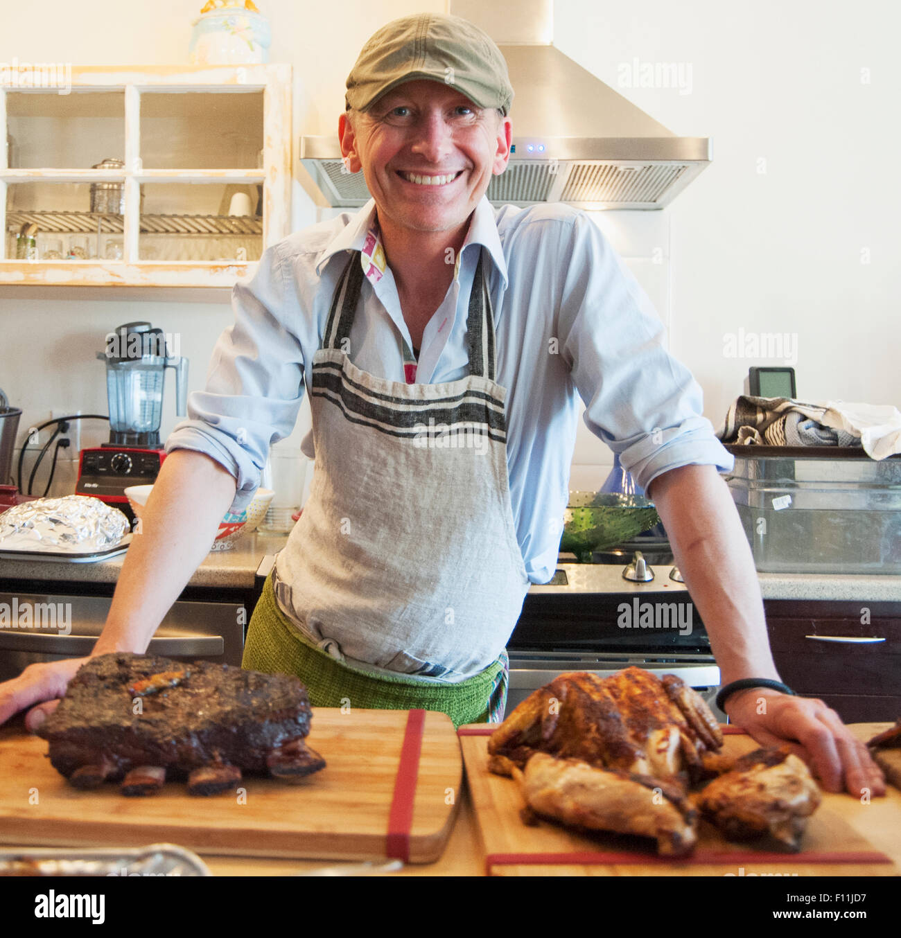 Mann lächelnd mit gebratenem Fleisch in Küche Stockfoto