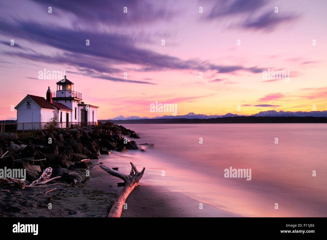 Verschwommene Sicht der Wellen am Strand von Leuchtturm bei Sonnenuntergang Stockfoto