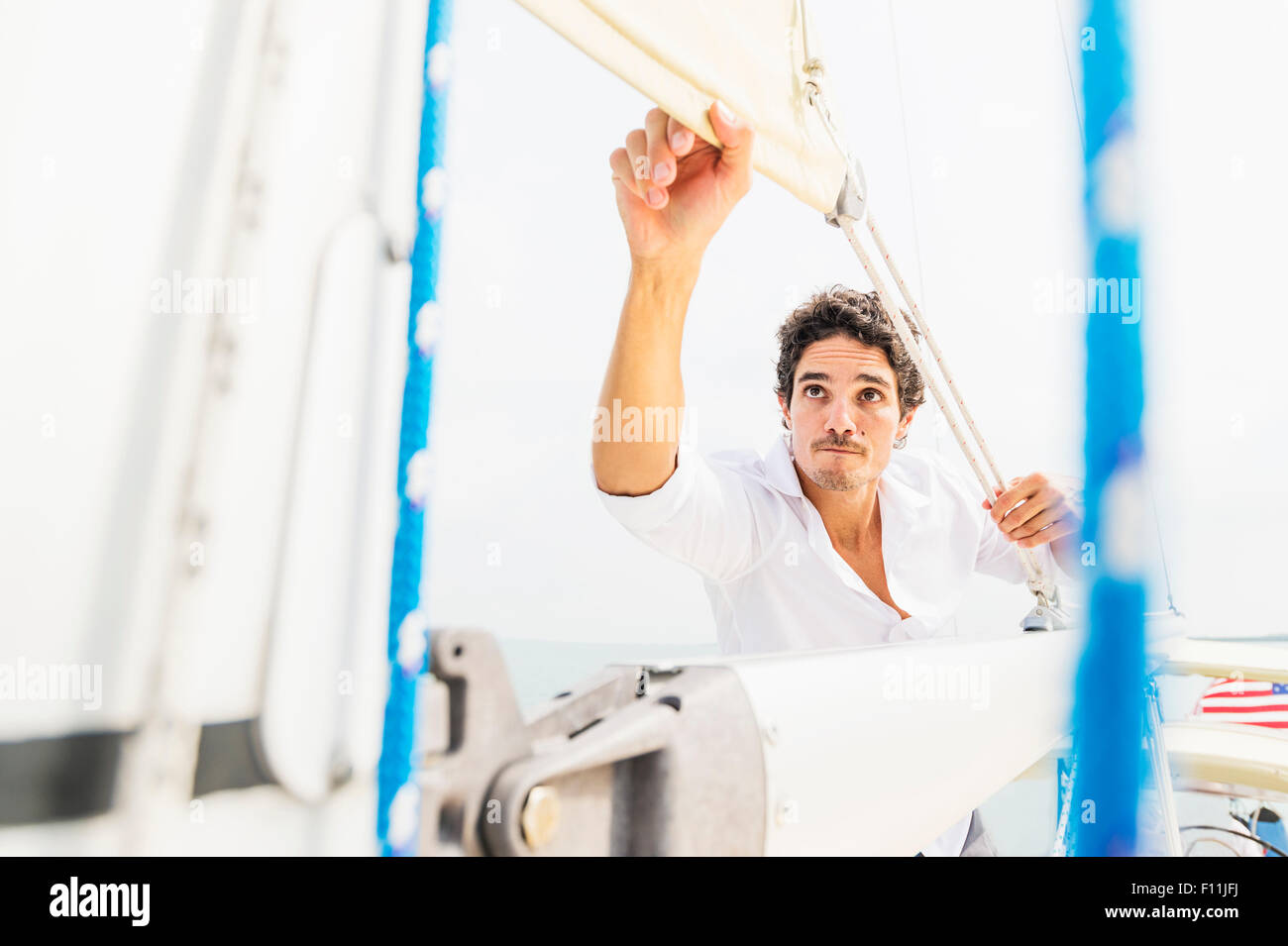Hispanic Mann Anpassung der Takelage auf Segelboot Stockfoto