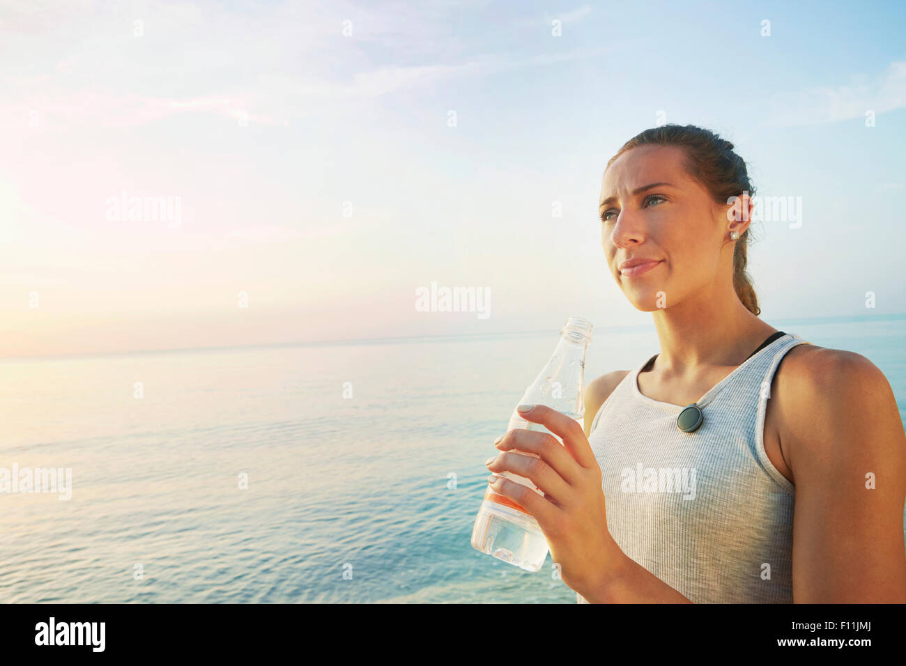 Athlet Trinkwasser Flasche am Strand Stockfoto