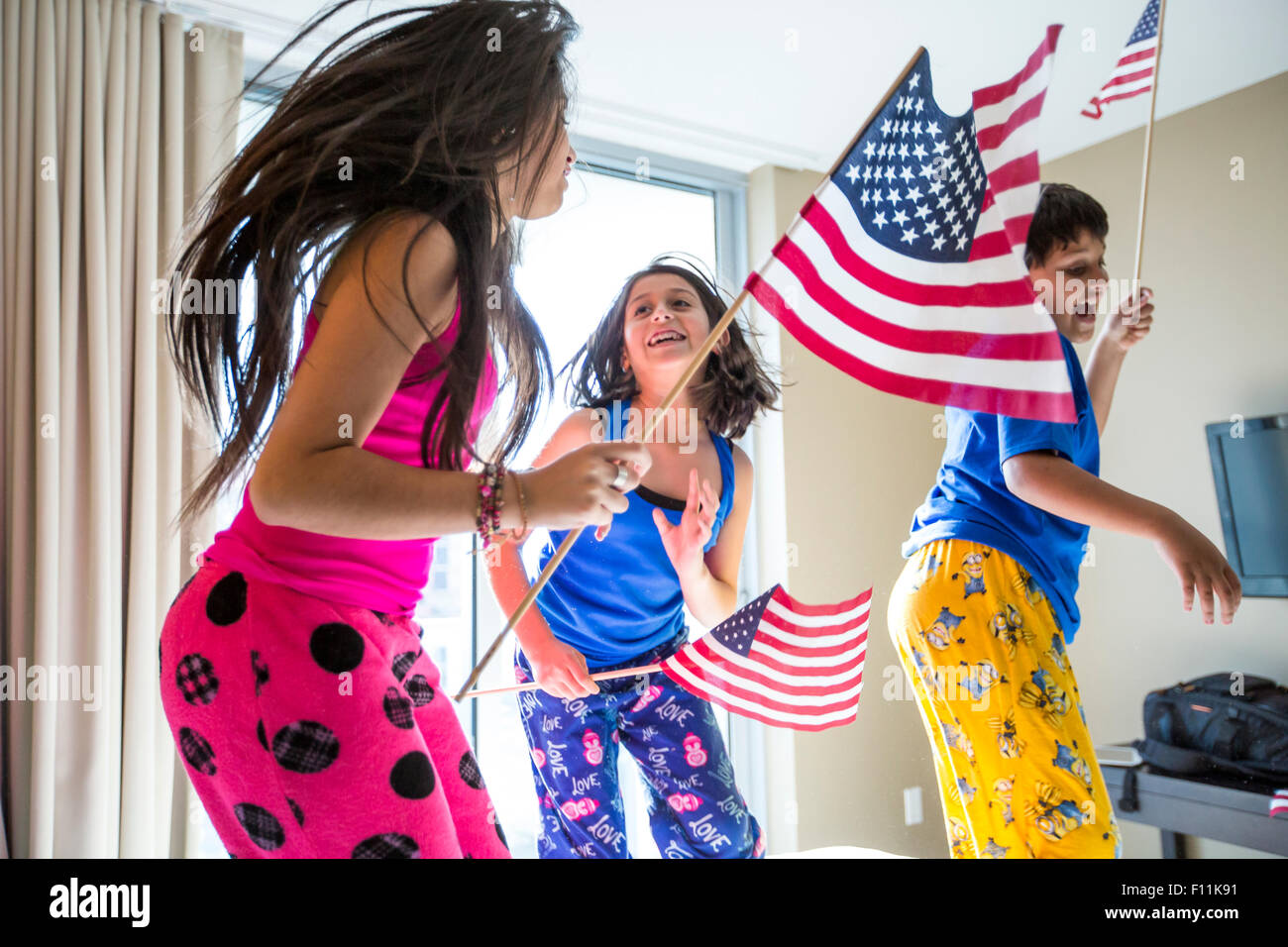 Hispanischen Kinder springen mit amerikanischen Flaggen Stockfoto