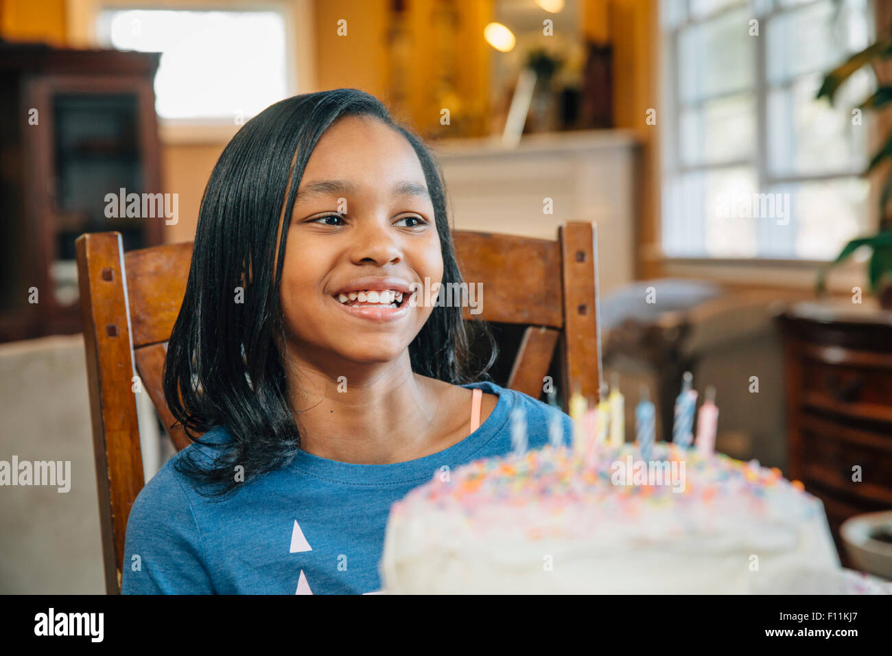 Schwarzes Mädchen bläst Kerzen auf Geburtstagskuchen Stockfoto