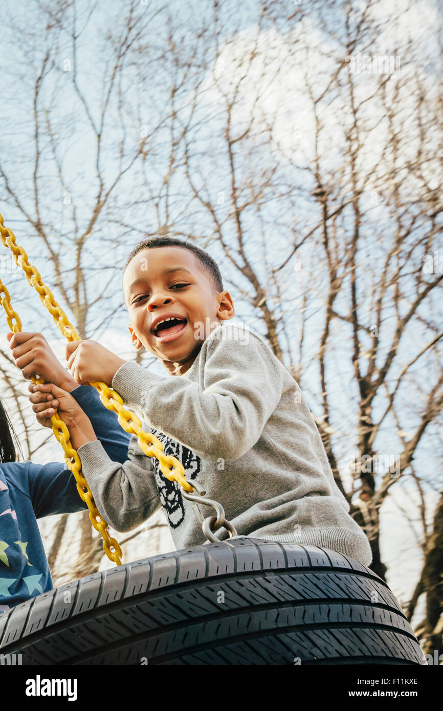 Schwarzer Junge spielt auf Reifenschaukel Stockfoto