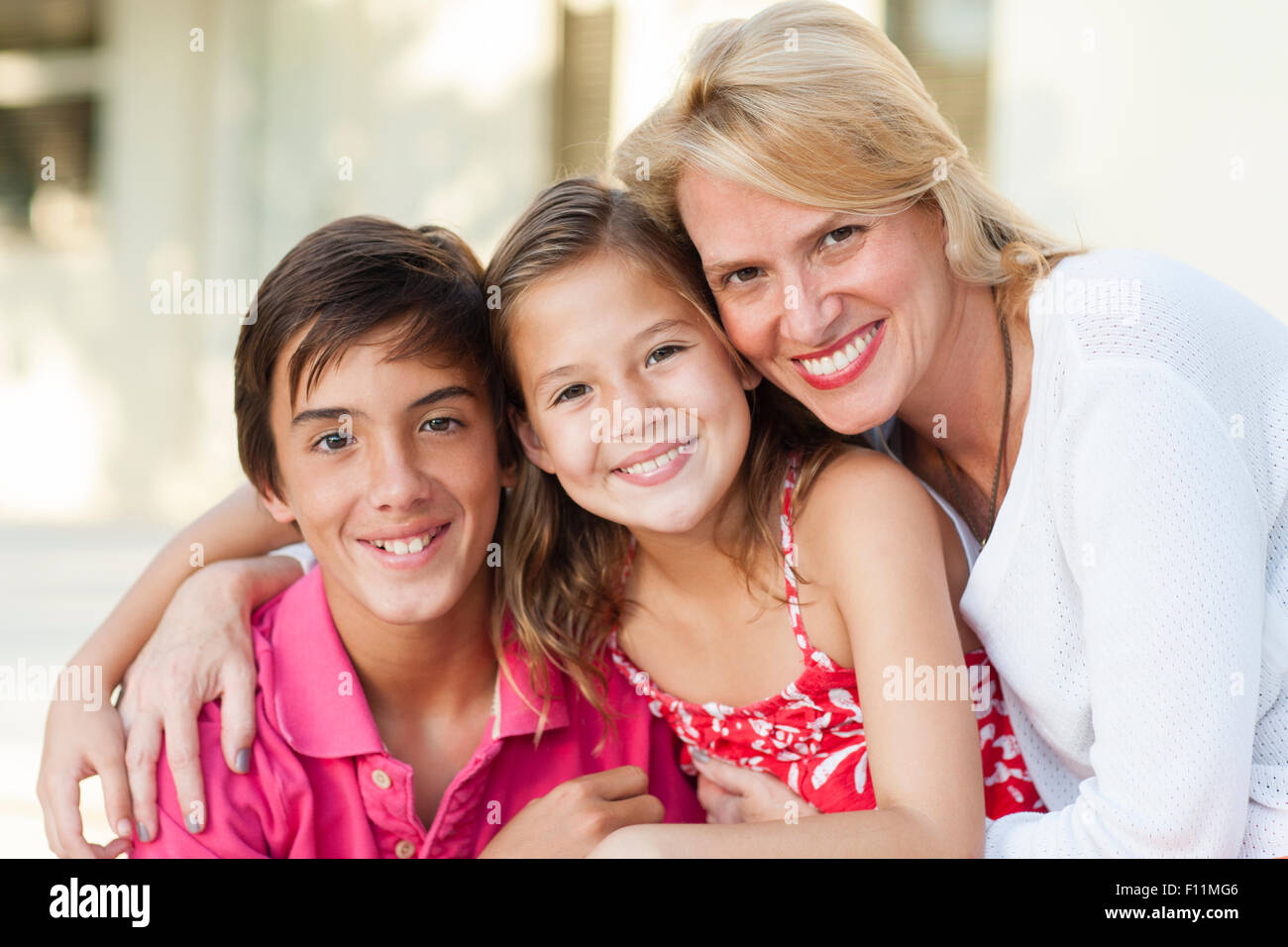 Lächelnde Mutter und Kinder umarmen im freien Stockfoto