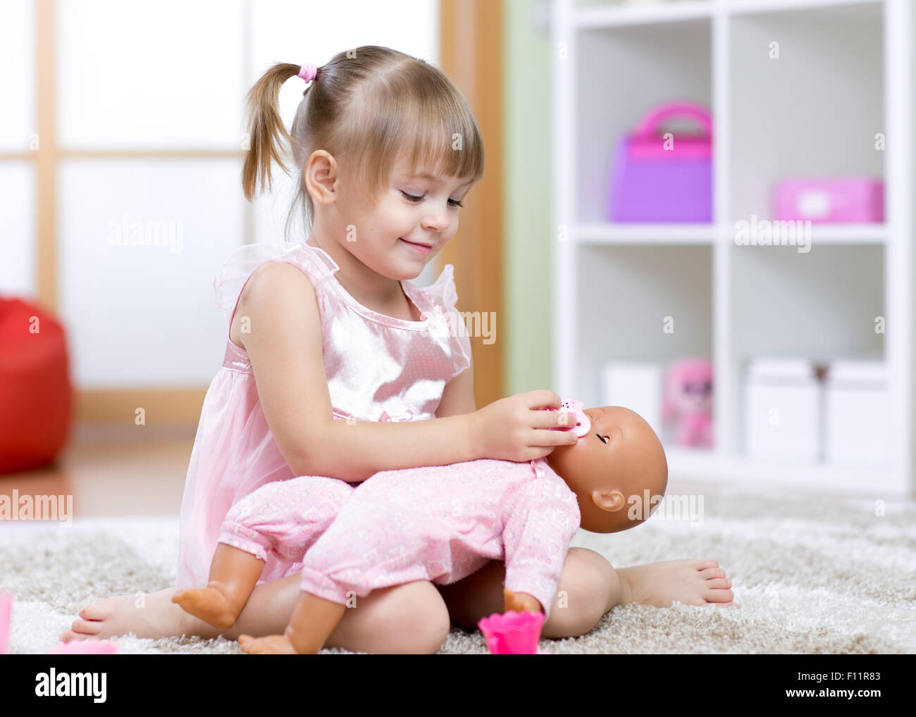 Schöne Mädchen spielen Arzt mit einer Puppe Stockfoto