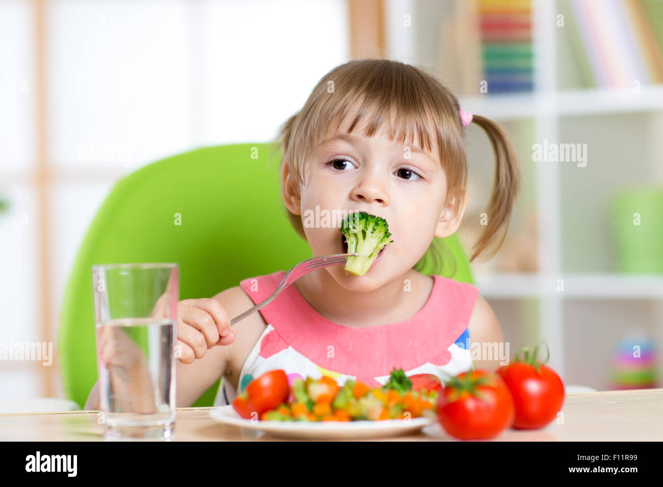 Niedliche kleine Mädchen isst Gemüsesalat mit Gabel Stockfoto