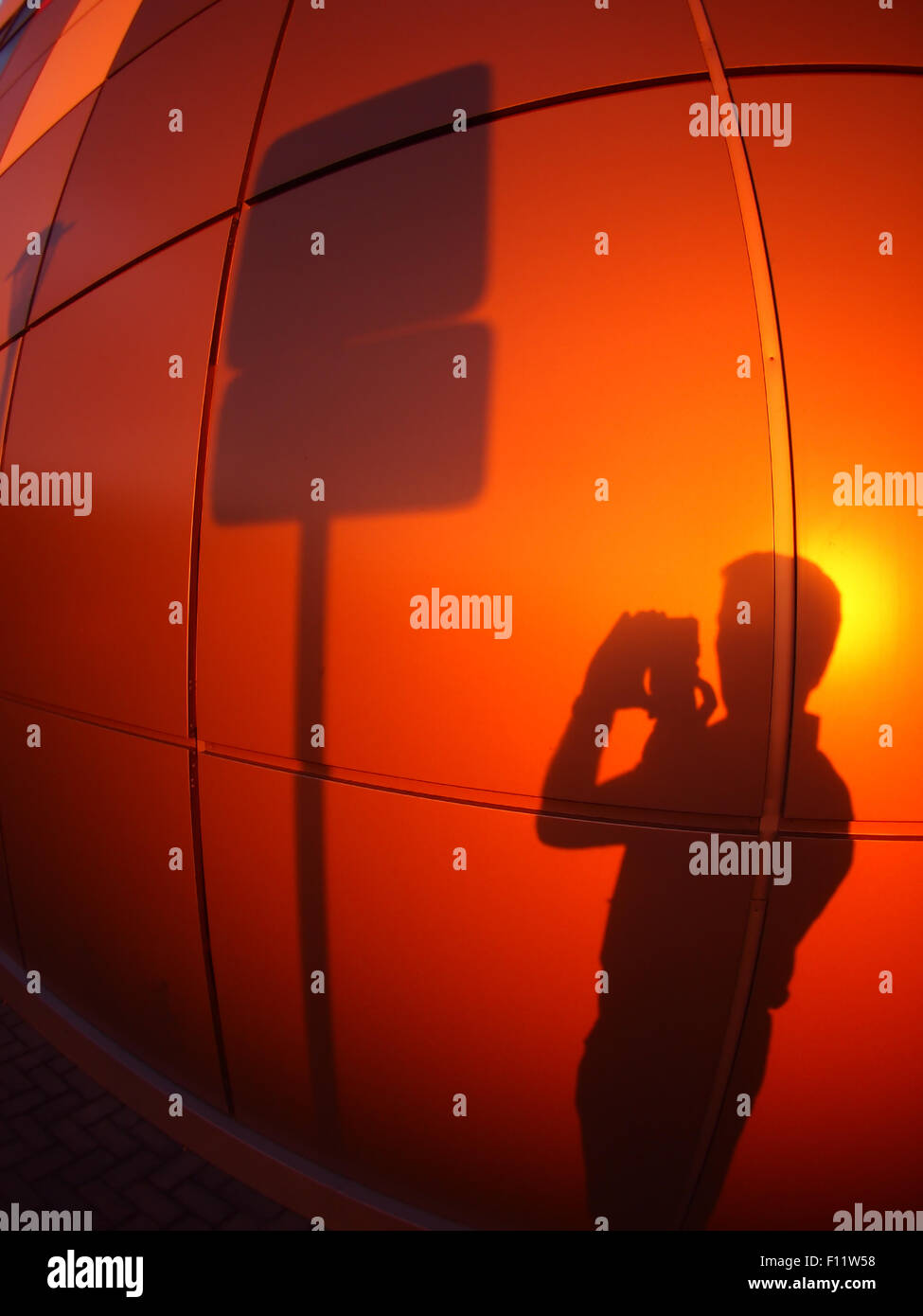 Der Schatten eines Mannes an eine Wand rot-Orange, eine Straße Fotos melden Sie sich am Abend bei Sonnenuntergang mit Weitwinkel fisheye-Objektiv und Stockfoto