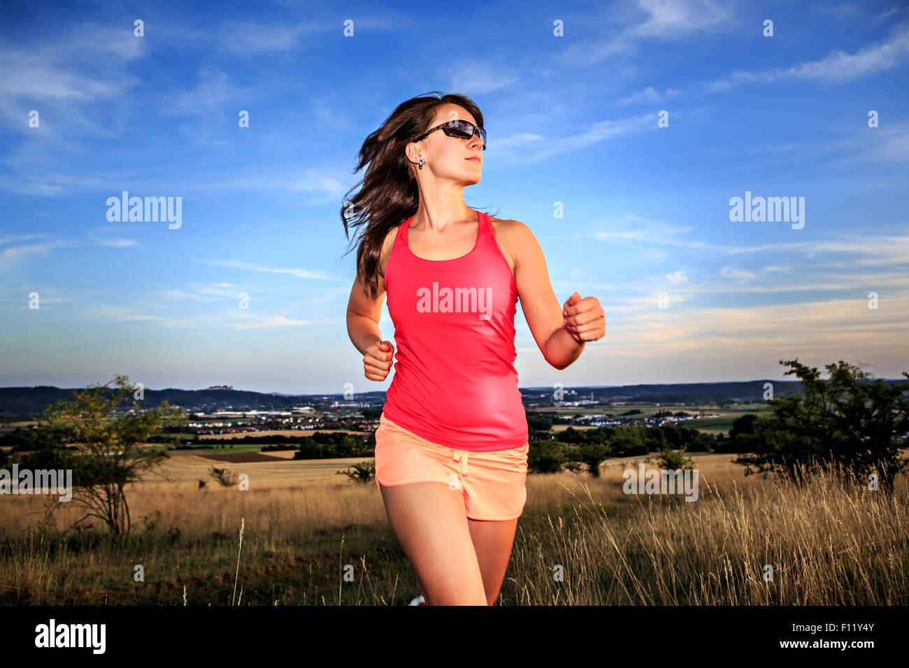junge Frau vor ländlichen Landschaft joggen Stockfoto