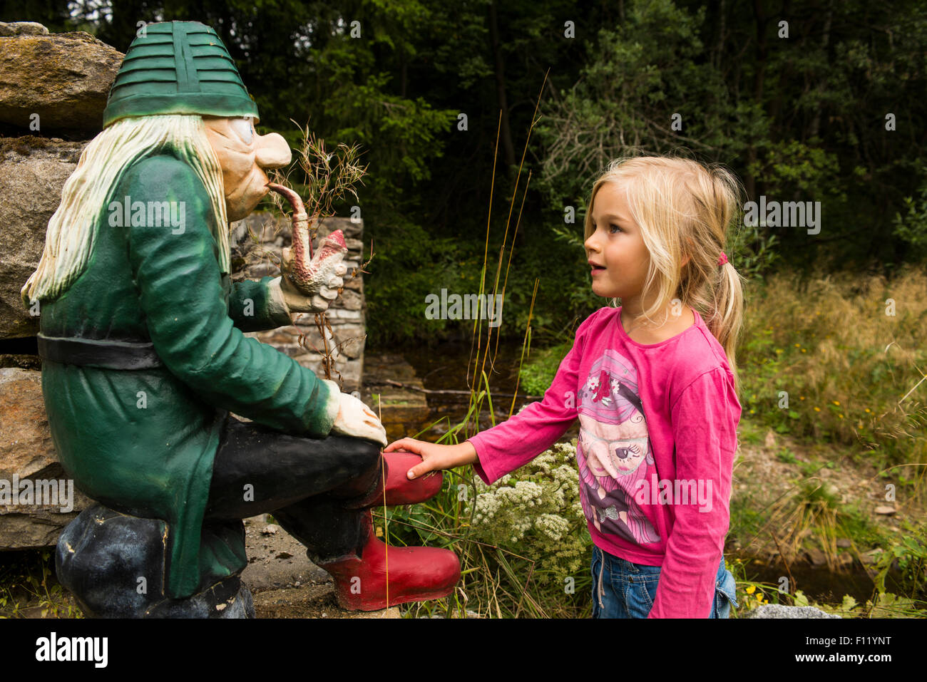 Kind etwas blondes Mädchen mit Wasser Sprite (Waterman) sitzen über stream Stockfoto