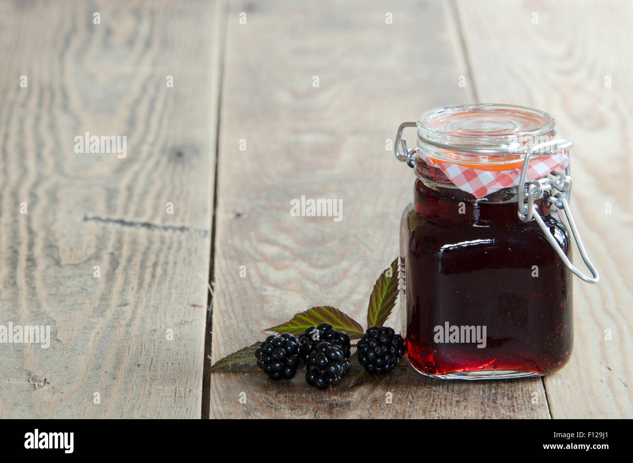 Ein Glas hausgemachte Blackberry Marmelade auf einem rustikalen hölzernen Hintergrund Stockfoto