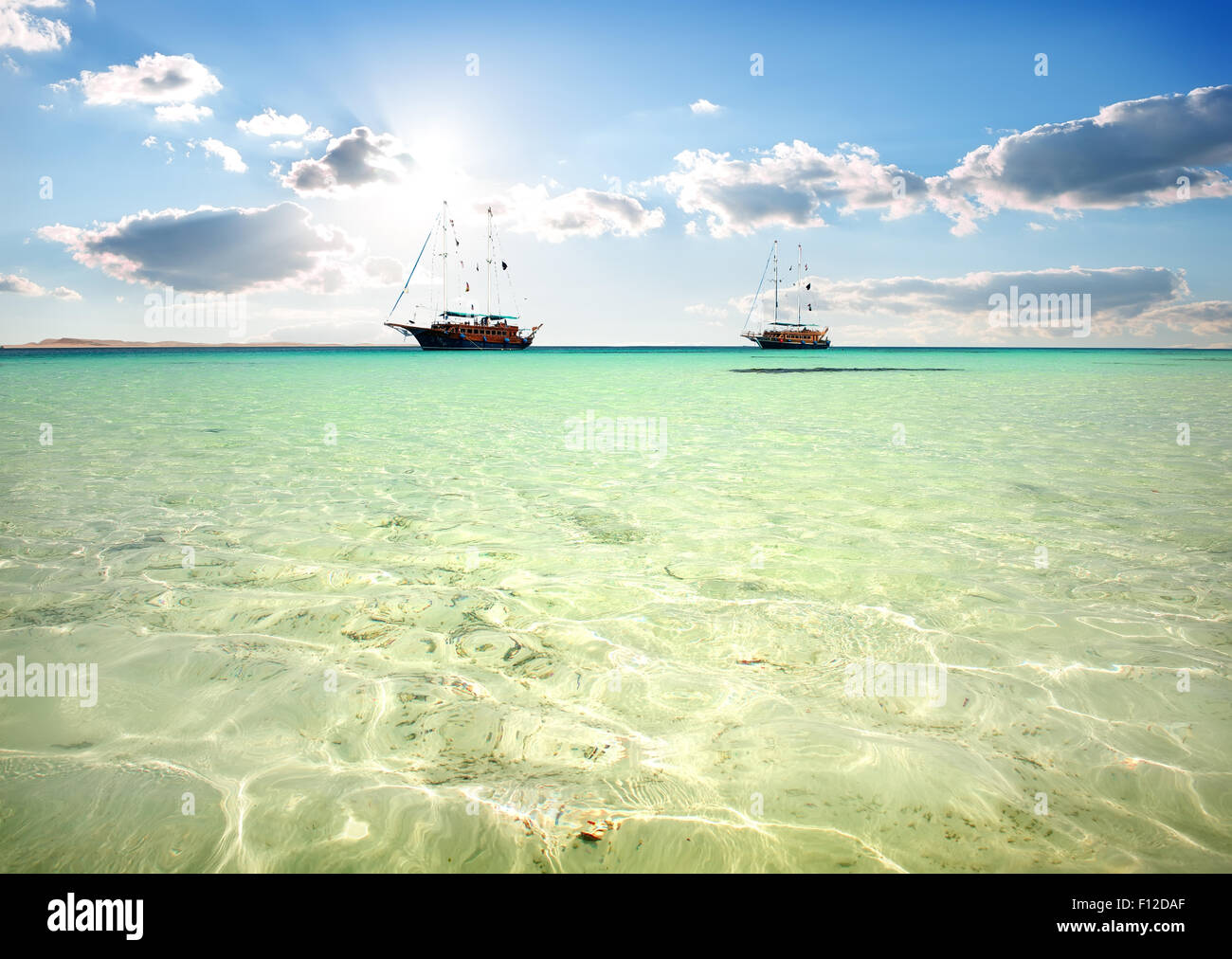 Zwei Segelboote im türkisfarbenen Meer unter Sonnenlicht Stockfoto