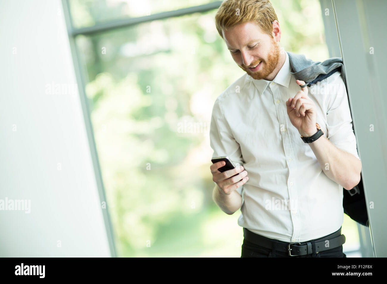Junger Mann mit Handy im Büro Stockfoto