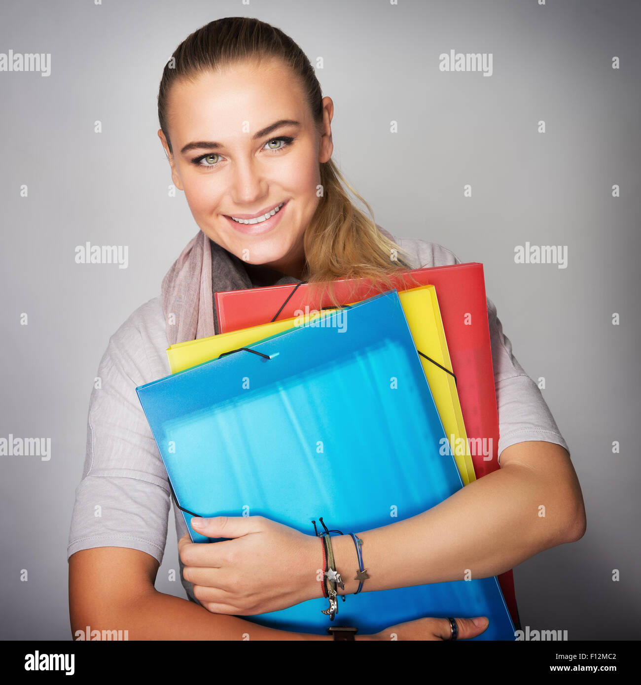 Schönes Schulmädchen Porträt über grauen Hintergrund, glückliche junge Frau genießen Bildung in der Schule Stockfoto