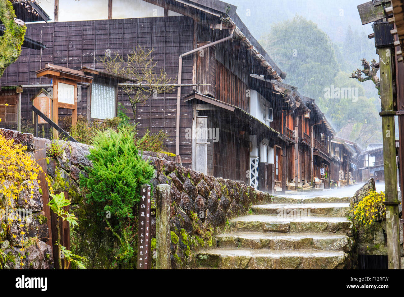 Tsumago, Japan. Terashita Straße auf dem alten Nakasendo Straße. Blick entlang der Edo Periode traditionelle 2-stöckiges Gebäude aus Holz in den strömenden Regen. Stockfoto