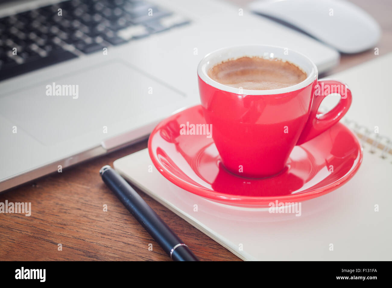 Rote Kaffeetasse mit Notizblock und Laptop, Fotoarchiv Stockfoto