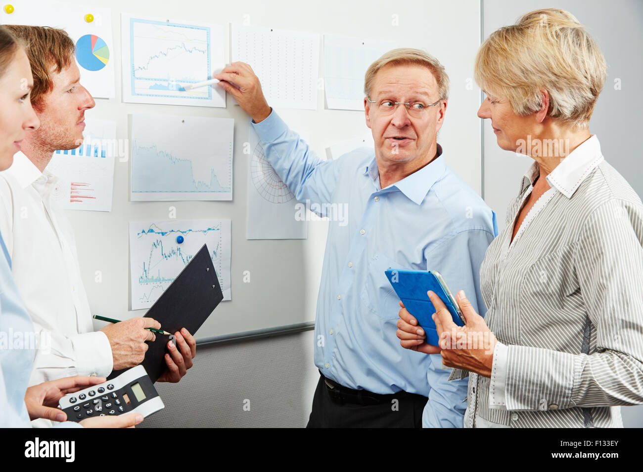 Berater im Business-Team erklärt Kursdiagramm auf andere Diagramme auf einem whiteboard Stockfoto