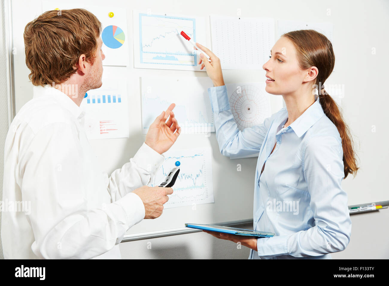 Zwei Menschen Diskussion finanzielle Geschäftsdaten auf einem whiteboard Stockfoto