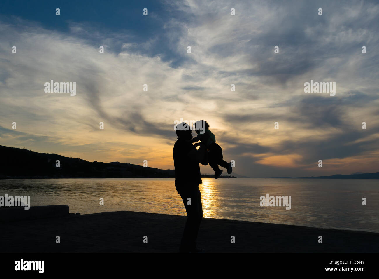 Vater und Sohn lieben Silhouette vor einem dramatischen Himmel. Stockfoto