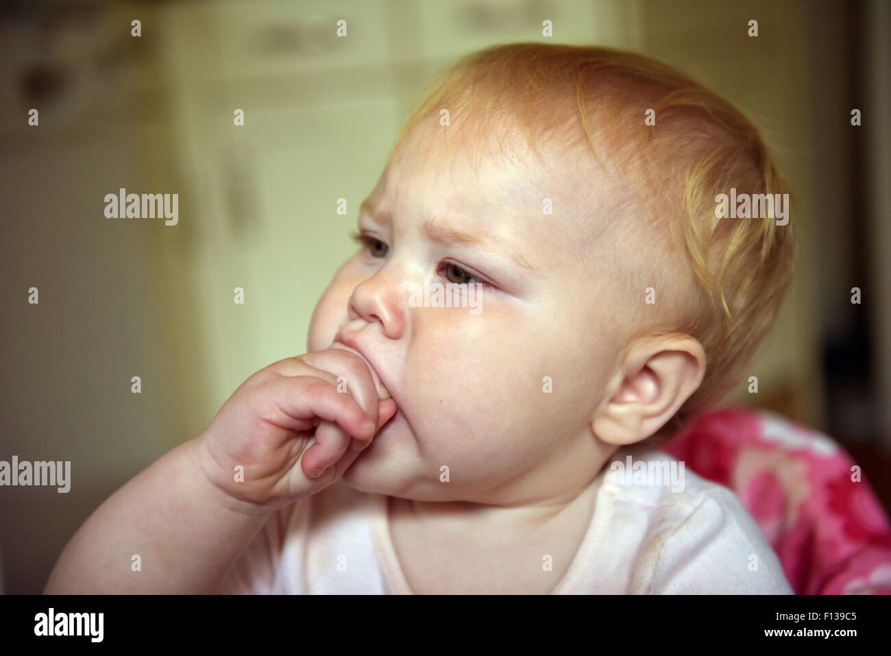 Ein elf Monate altes Baby an ihrer Hand kauen, die Schmerzen und Beschwerden des Zahnes zu lindern Schmerzen. Stockfoto