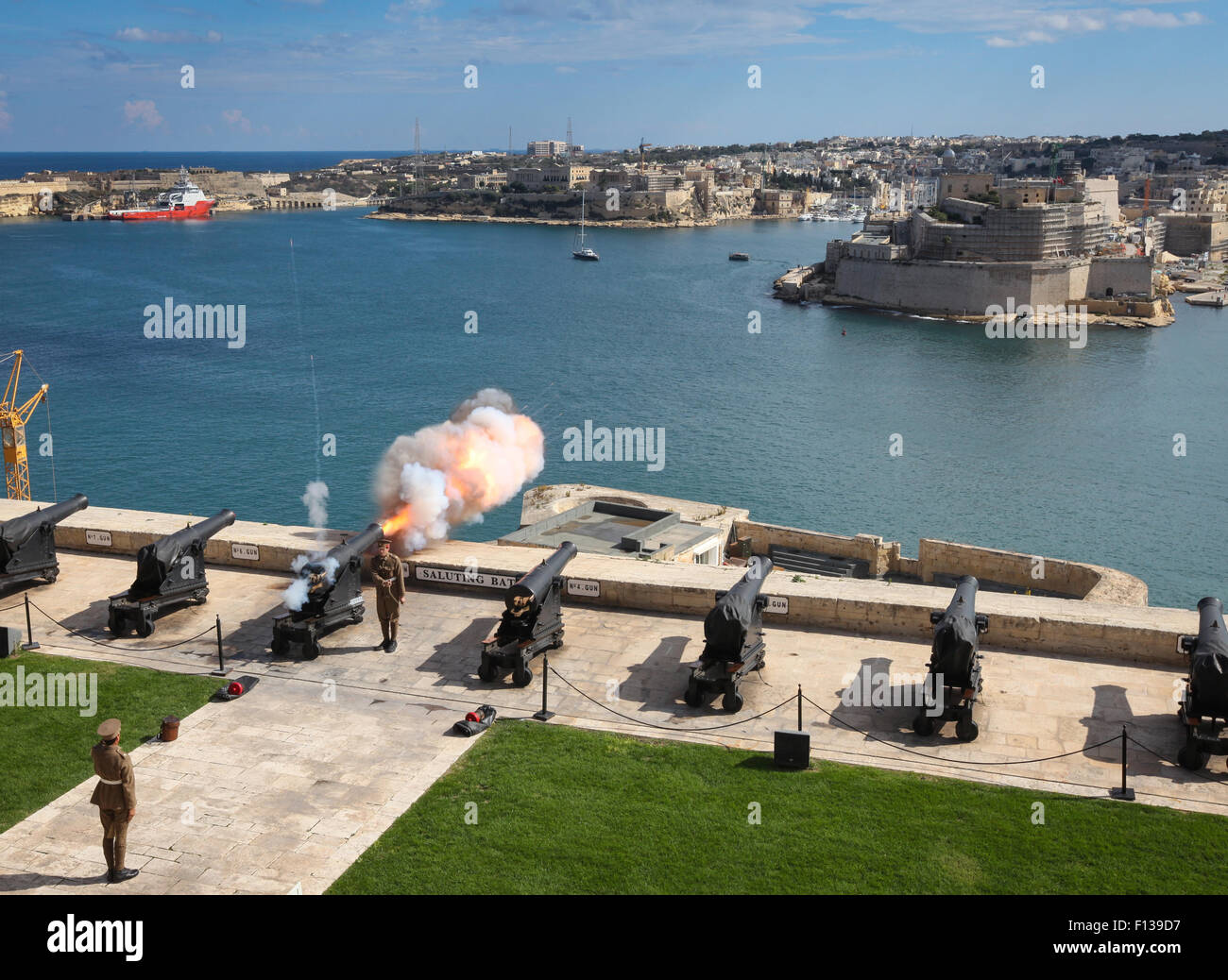 Brennen der Mittag Tag Waffe auf salutieren, Batterie, Upper Barracca Gardens, und Grand Harbour, Valletta, Malta Stockfoto