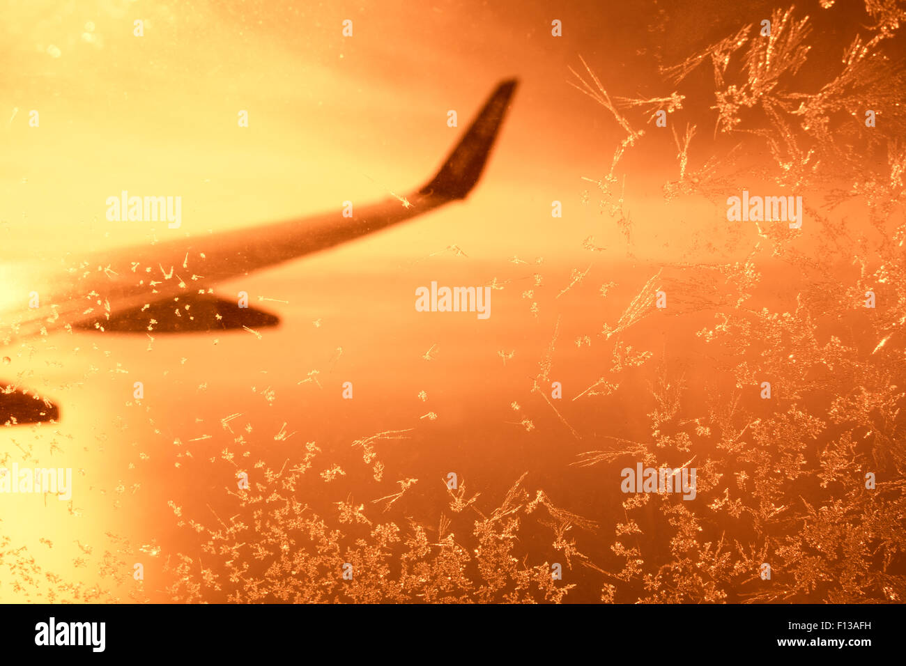 Blick aus satiniertem Flugzeugfenster bei Sonnenuntergang Stockfoto