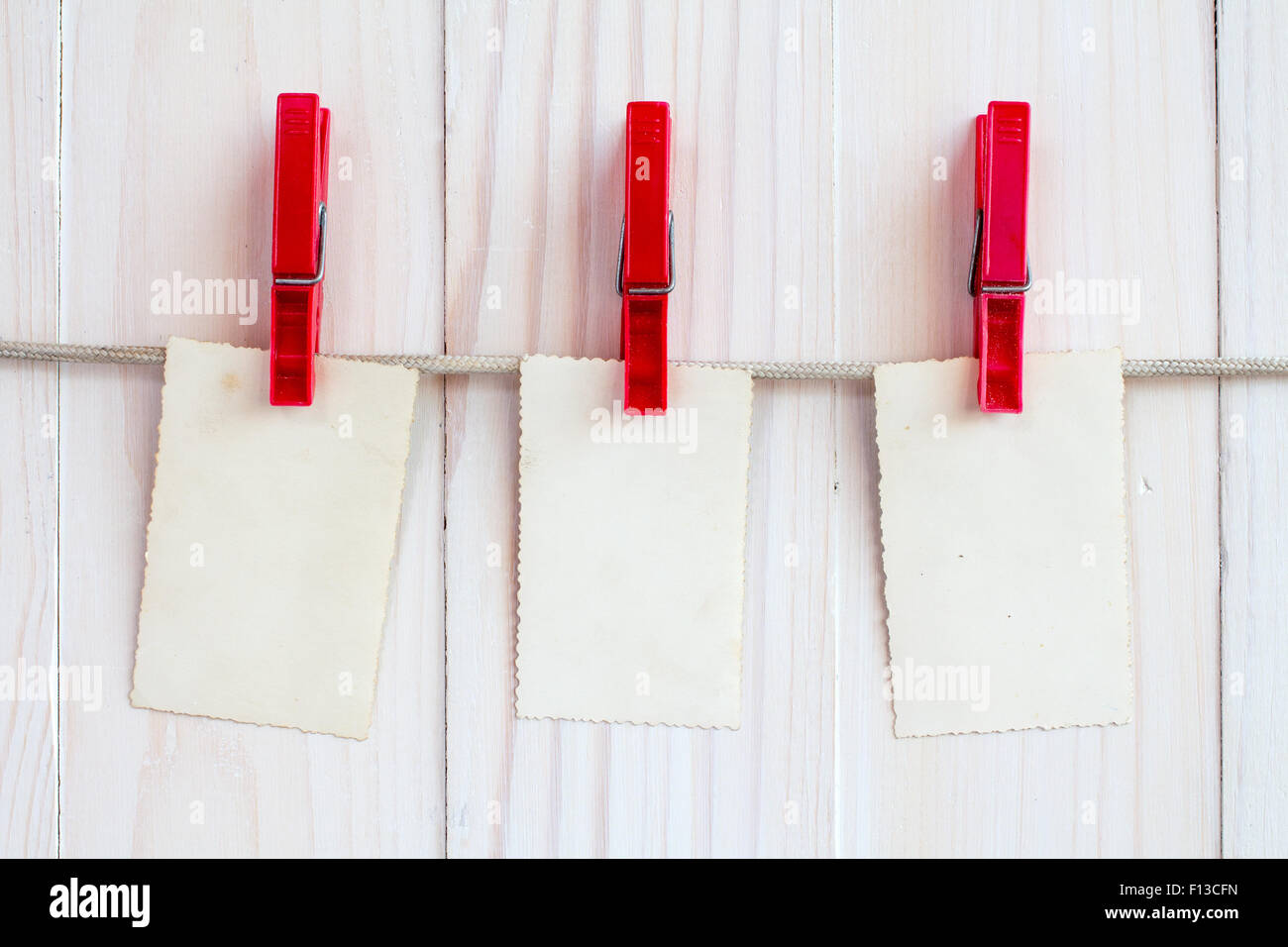 Digitale Bilderrahmen hängen an einem Seil über weißem Holz Hintergrund Stockfoto
