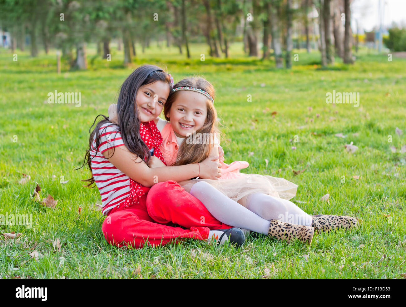 Zwei Mädchen sitzen im Park, umarmen Stockfoto