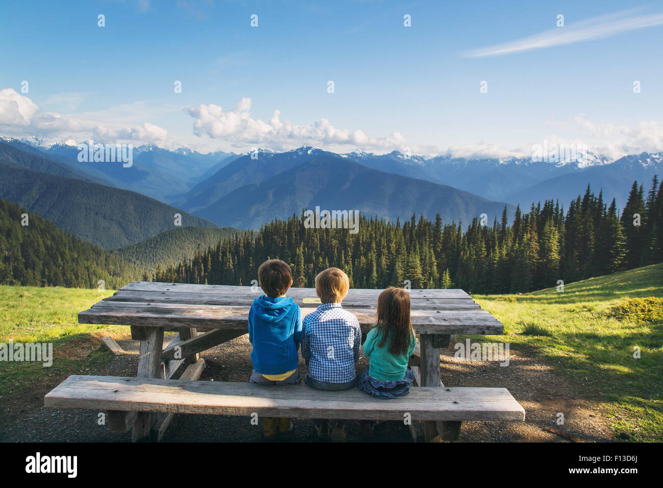 Rückansicht von drei Kindern, die auf einer Bank sitzen und die Ansicht, USA, betrachten Stockfoto