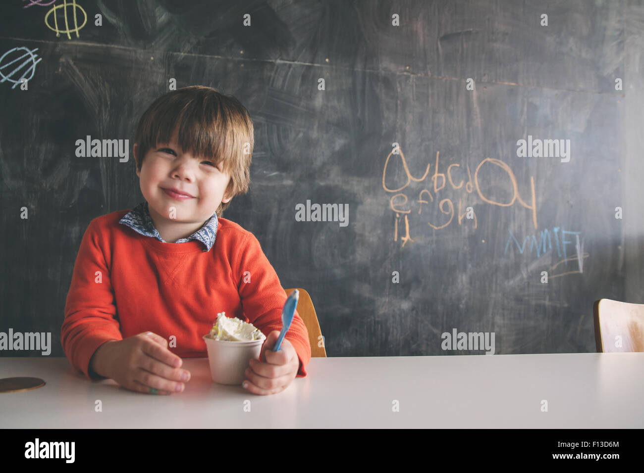 Lächelnde junge sitzt am Tisch mit einem Eis Stockfoto