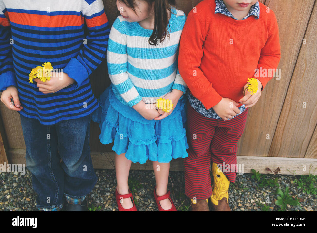 Drei Kinder stehen in einer Reihe mit Blumen Stockfoto