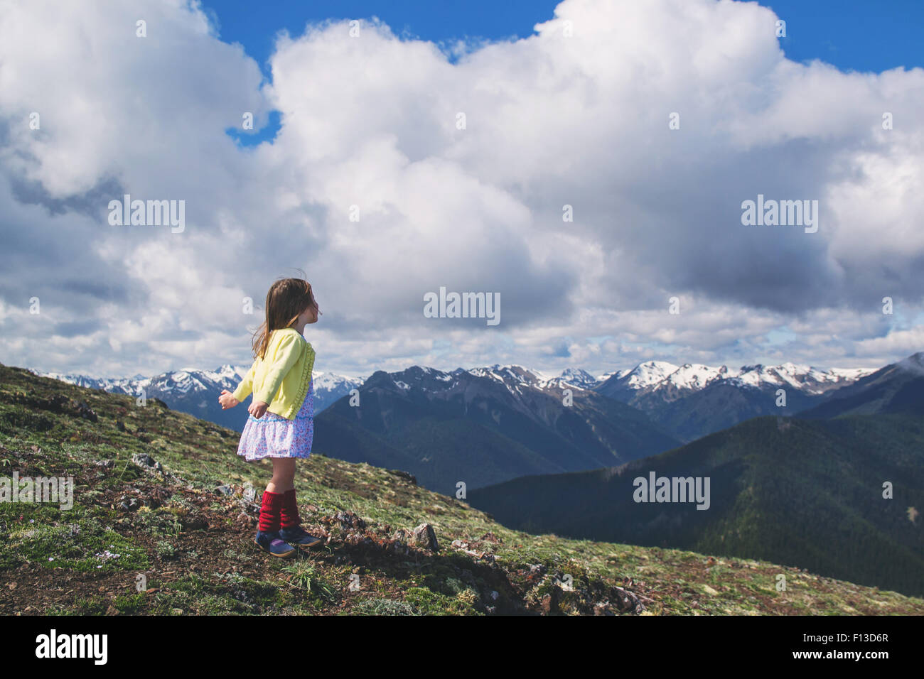 Kleines Mädchen mit ausgestreckten Armen auf Berg stehend Stockfoto