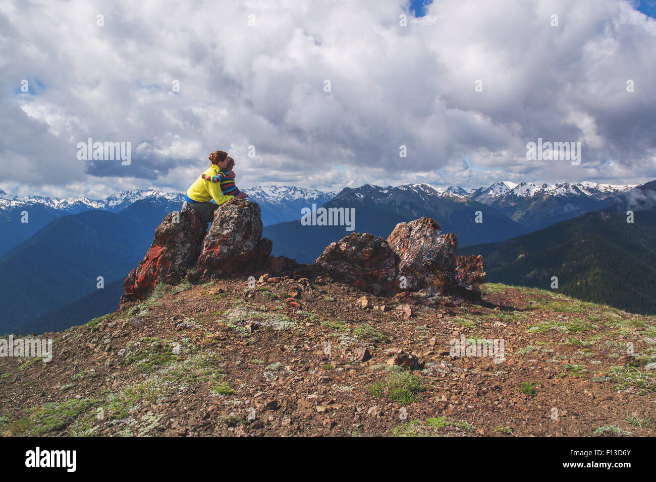 Mutter saß auf einem Felsen am Berg umarmt ihren Sohn Stockfoto